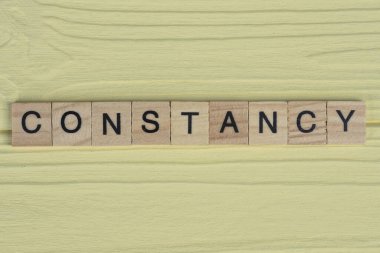 Gri küçük tahta harflerin sabiti sarı ahşap bir masada yatar.