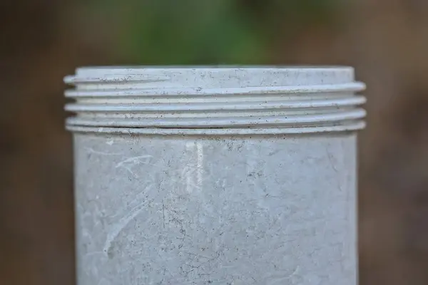 Kahverengi Arka Planda Iplikleri Olan Beyaz Kirli Bir Plastik Borunun — Stok fotoğraf