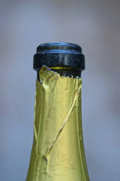 green glass bottle neck in yellow foil on a gray background