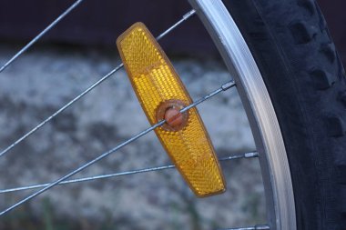 Gri metal tellerde eski bir plastik yansıtıcı Sokaktaki bisiklet tekerleğinde