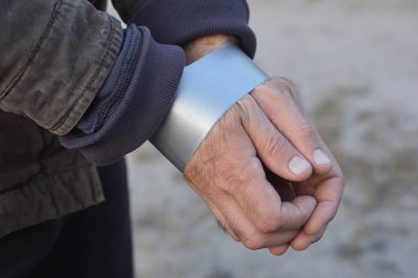 Erkek bir suçlunun elleri bağlanır ve gri bir arka planda gri bantla sarılır.