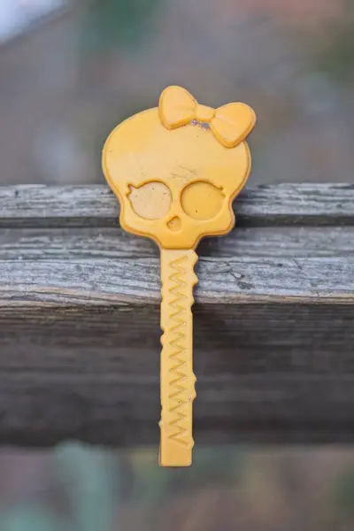 one small plastic yellow skull toy with a bow on a stick lies on a gray wooden table