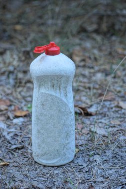 Kirli, eski, beyaz bir plastik şişenin çöpleri sokaktaki gri zeminde duruyor.