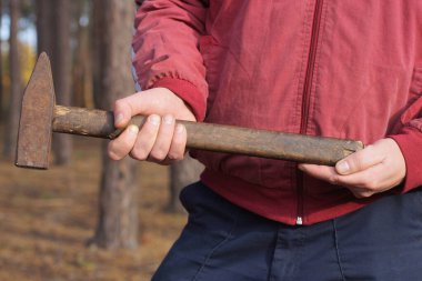Kırmızı elbiseli bir işçinin elleri caddede büyük kahverengi bir çekiç tutuyor.