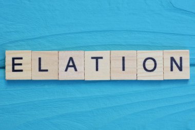 Mutluluk kelimesi ahşap gri harflerden yapılmıştır. Mavi arka planda yatar.