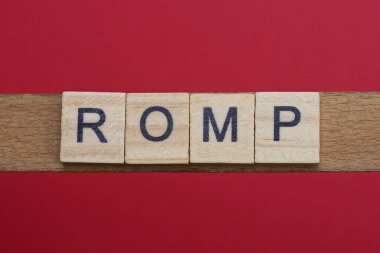 Gri ahşap harflerle kırmızı masada siyah yazı tipi olan romp sözcüğünü yaz.