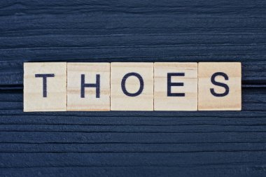 Kahverengi ahşap küçük harflerden gelen kelimeleri siyah bir masanın üzerine yaz.