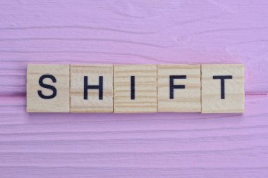 Kelime kaydırma küçük gri ahşap harfler pembe ahşap masa üzerinde yatıyor