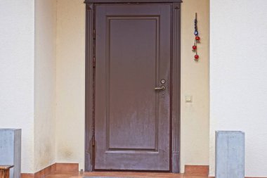 Kapalı kahverengi plastik bir kapı. Caddedeki gri bir evin duvarında.