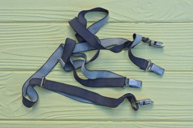  Askıda metal çıtçıtlı dört gri kumaş koşum takımı sarı ahşap bir masada yatıyor.