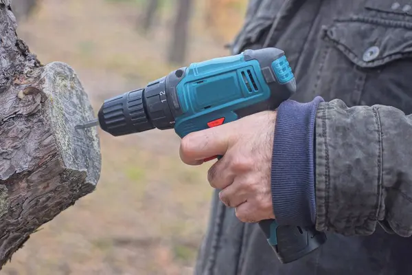 Tornavidayla çalışan bir işçi sokakta gri bir tahta kazık deliyor.