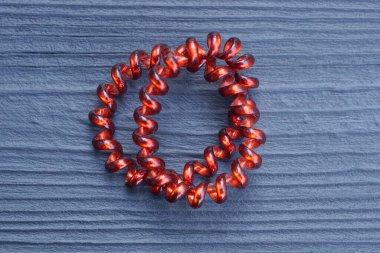 Kablodan yapılmış kırmızı plastik bir bilezik siyah tahta bir masanın üzerinde duruyor.