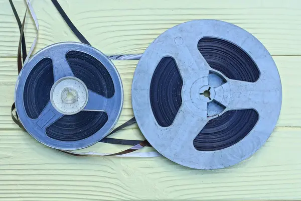 two old plastic black gray magnetic reels for a tape recorder lie on a yellow wooden table