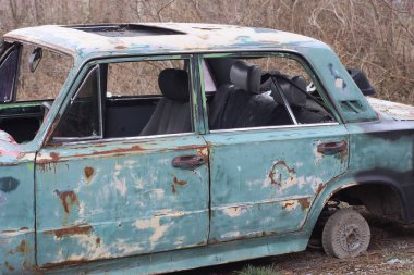 Eski, yeşil, parçalanmış bir yolcu arabası sokakta duruyor.