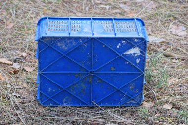 Eski mavi bir plastik kutu Gri zeminde duruyor Sokakta