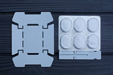 Siyah ahşap bir masada üzerinde beyaz alkol yakıtı bulunan taşınabilir gri metal yakıcı paketler var.