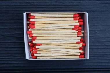 Bir kibrit kutusu siyah ahşap bir masada duruyor.