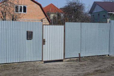 gray long metal fence wall and closed door in the rural street