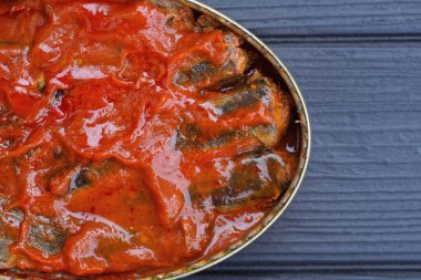 Domates soslu sardalya balığıyla birlikte açık bir almina oval teneke kutu siyah ahşap bir masanın üzerinde yatıyor.