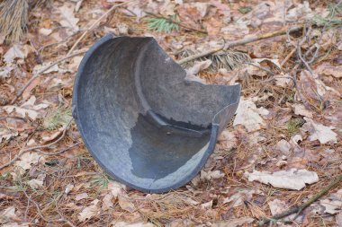 Kırık bir siyah plastik kovanın çöpü, sokaktaki gri zeminde duruyor.