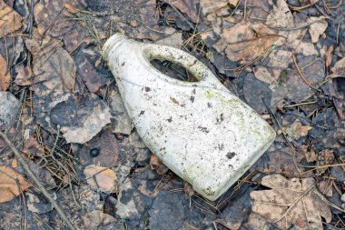 Eski beyaz plastik bir teneke kutu çöp gri toprak ve sokakta gri kahverengi yapraklar yatar
