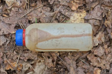 Eski beyaz plastik bir teneke kutu çöp gri toprak ve sokakta gri kahverengi yapraklar yatar