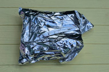 Bir adet kapalı gri plastik poşet sarı bir masanın üzerinde duruyor.