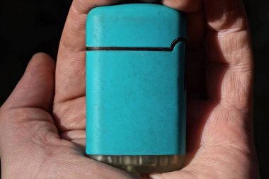 Açık havada mavi bir çakmağı tutan el. 