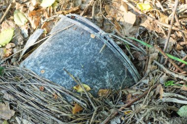 Kırık bir siyah plastik kovanın çöpü, sokaktaki gri zeminde duruyor.