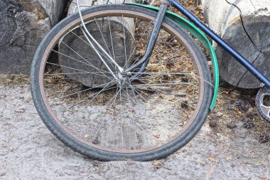 Gri kumlar ve caddelerdeki ahşap kütükler üzerinde eski bir bisiklet yatıyor.