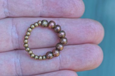 Bir kahverengi bakır yüzük, elin parmaklarında duruyor.