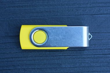 Siyah ahşap bir masada küçük, gri, kapalı bir taşınabilir bellek duruyor.