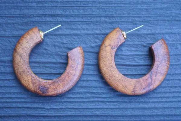 stock image two round brown earrings lie on a black wooden table