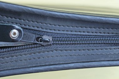 Sarı arka planda siyah deri bir çantaya kapalı bir fermuar bağlayıcı.