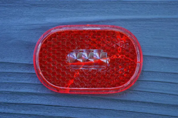 stock image one red plastic reflector lies on a black wooden table