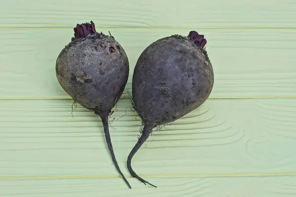 stock image two gray raw beets lie on a yellow wooden table