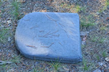 Eski, kirli bir koltuk yere uzanıyor ve dışarıda yeşil çimenler var.