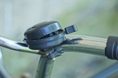 Gri metal bisiklet gidonunda siyah kırık bir plastik zil.