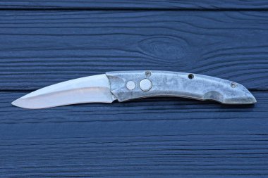 Bir gri metal katlanır bıçak siyah tahta bir masanın üzerinde yatıyor.