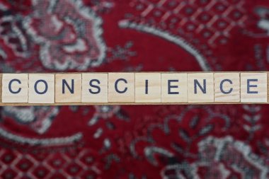 Vicdan kelimesini kırmızı bir masada siyah yazı tipi olan gri ahşap harflerden yaz.