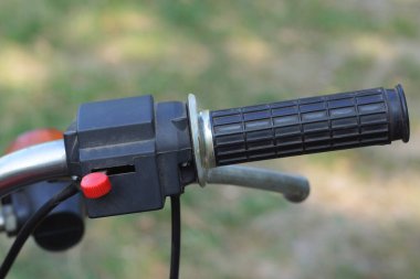 Yazlık sokakta siyah gri direksiyonlu eski bir motosikletin parçası.