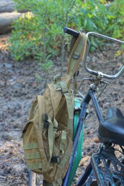 Kahverengi bir ordu sırt çantası eski bir bisikletin gidonuna asılı.
