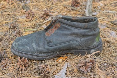 Eski, kirli, siyah bir çizme sokakta yerde duruyor.