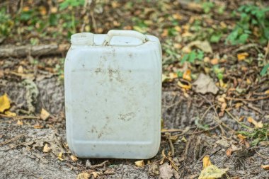 Eski, kirli, beyaz plastik bir teneke kutunun çöpü, sokaktaki gri zeminde duruyor.