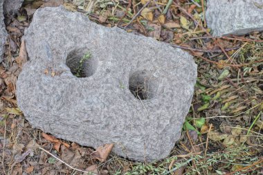 Eski, kirli, büyük bir gri tuğla parçası caddenin kahverengi zemininde yatıyor.