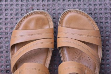 İki deri kahverengi sandalet yerde duruyor.