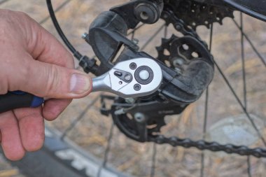 İngiliz anahtarıyla bir el sokağın ortasında bir bisikletin vidasını söker.