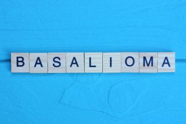 word basalioma made from wooden gray letters lies on a blue background clipart