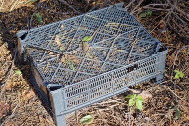 Siyah kırık bir plastik kutu sokakta yerde duruyor.