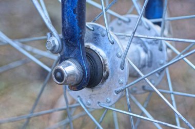 Bir yaz caddesinde bisikletin ön tekerleğinde telleri olan gri metal bir merkez.